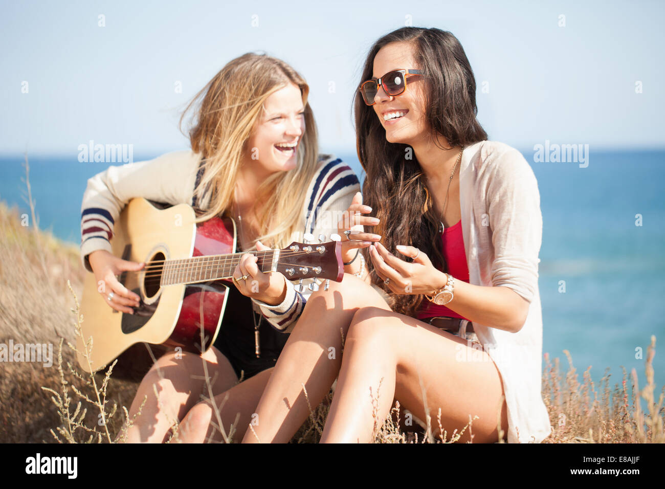 Two young women with acoustic guitar at coast, Malibu, California, USA Stock Photo