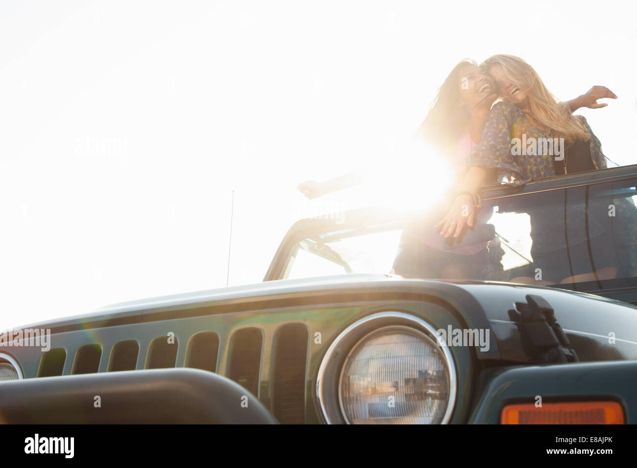 Two young women standing up in back of jeep Stock Photo