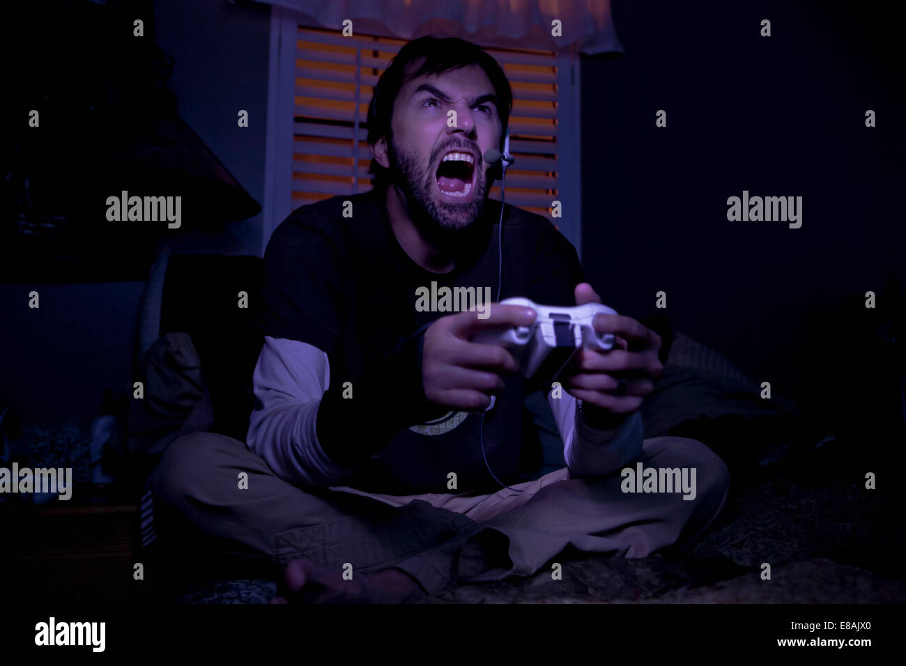 Mid Adult Man Shouting Whilst Playing Video Game At Night Stock
