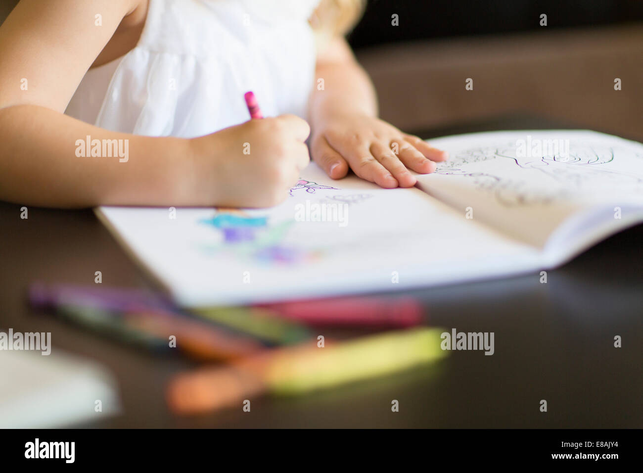 Cropped shot of girl coloring in book with crayons Stock Photo