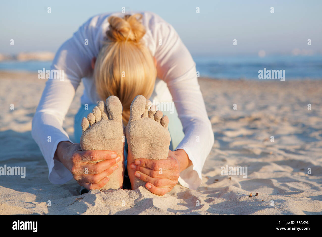 Woman doing yoga prayer stretch on the beach Stock Photo