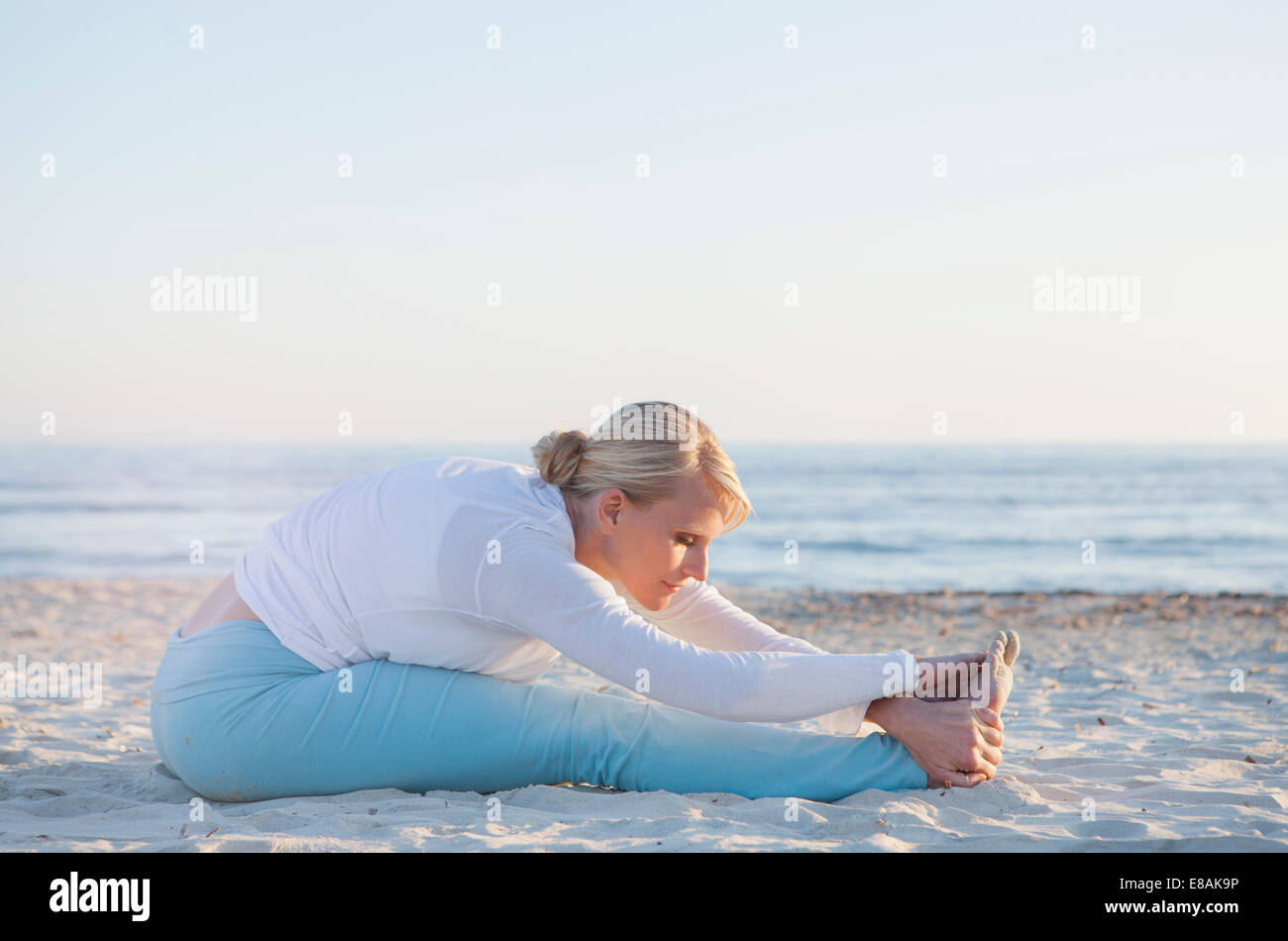 Woman doing yoga prayer stretch on the beach Stock Photo