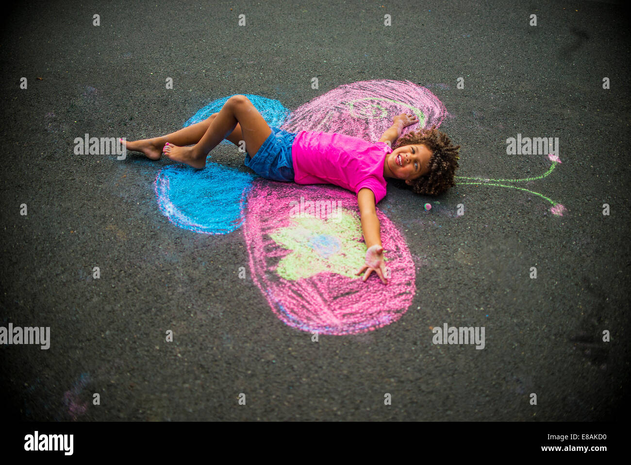 Young girl lying on floor between chalked butterfly wings Stock Photo
