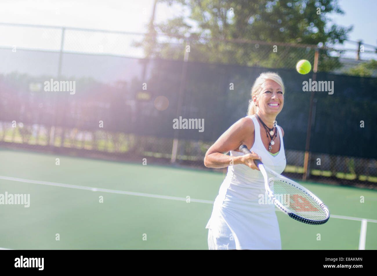 Smiling mature woman playing tennis Stock Photo
