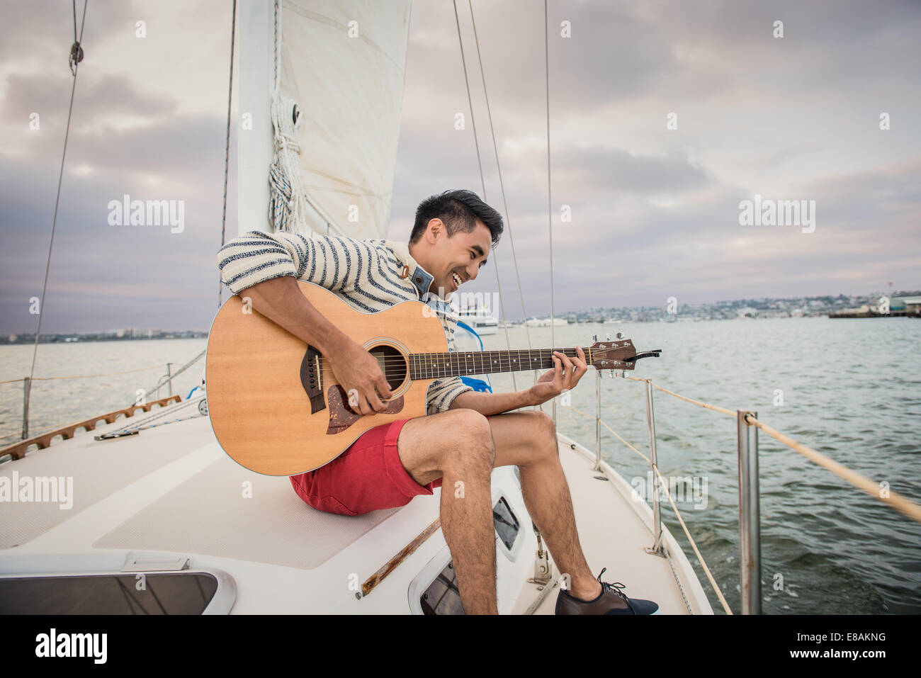 Young man on sailing boat playing guitar Stock Photo