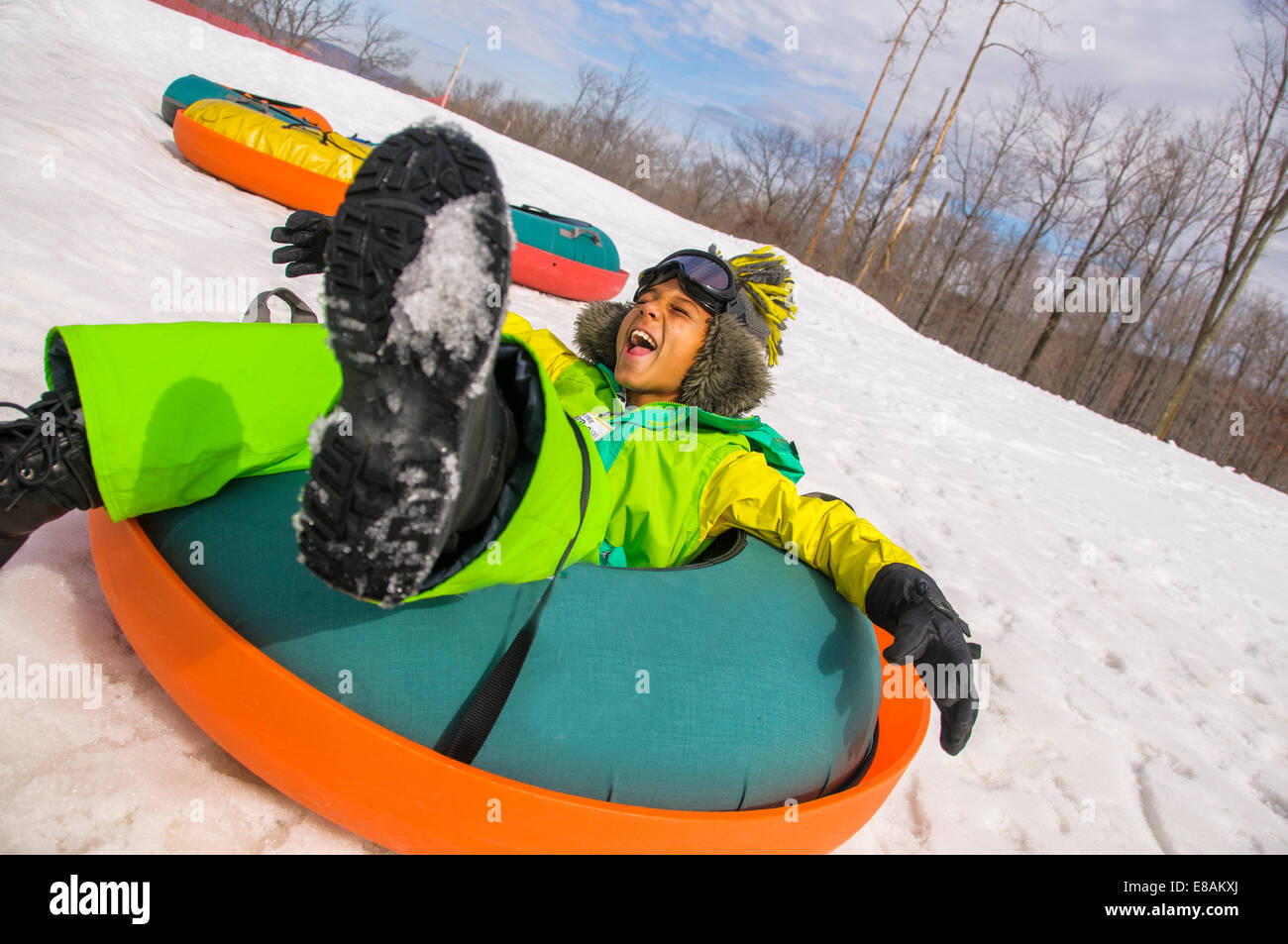 Boy laughing whilst tobogganing down hires stock photography and
