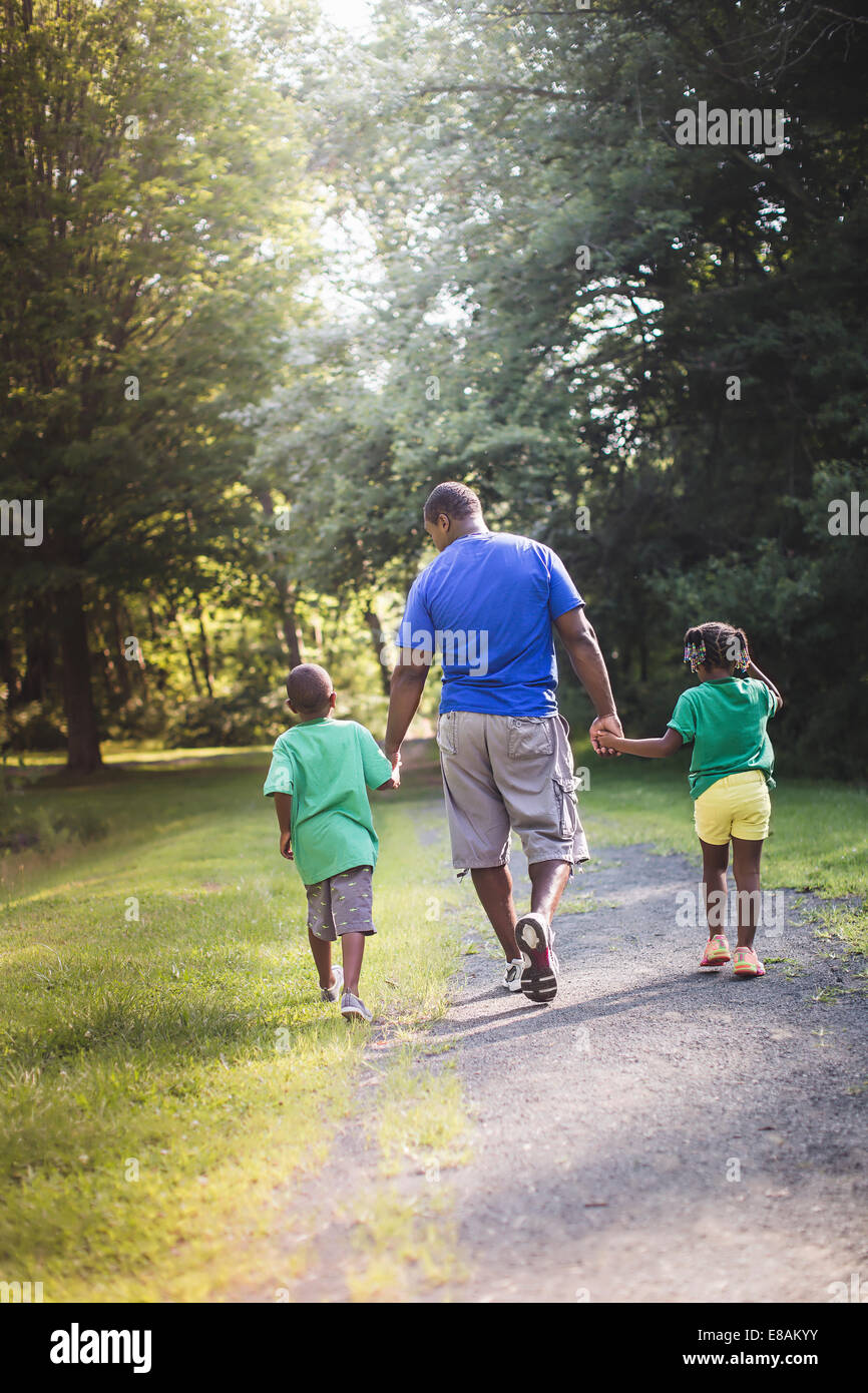 Rear view of father holding hands with son and daughter at parkland eco camp Stock Photo