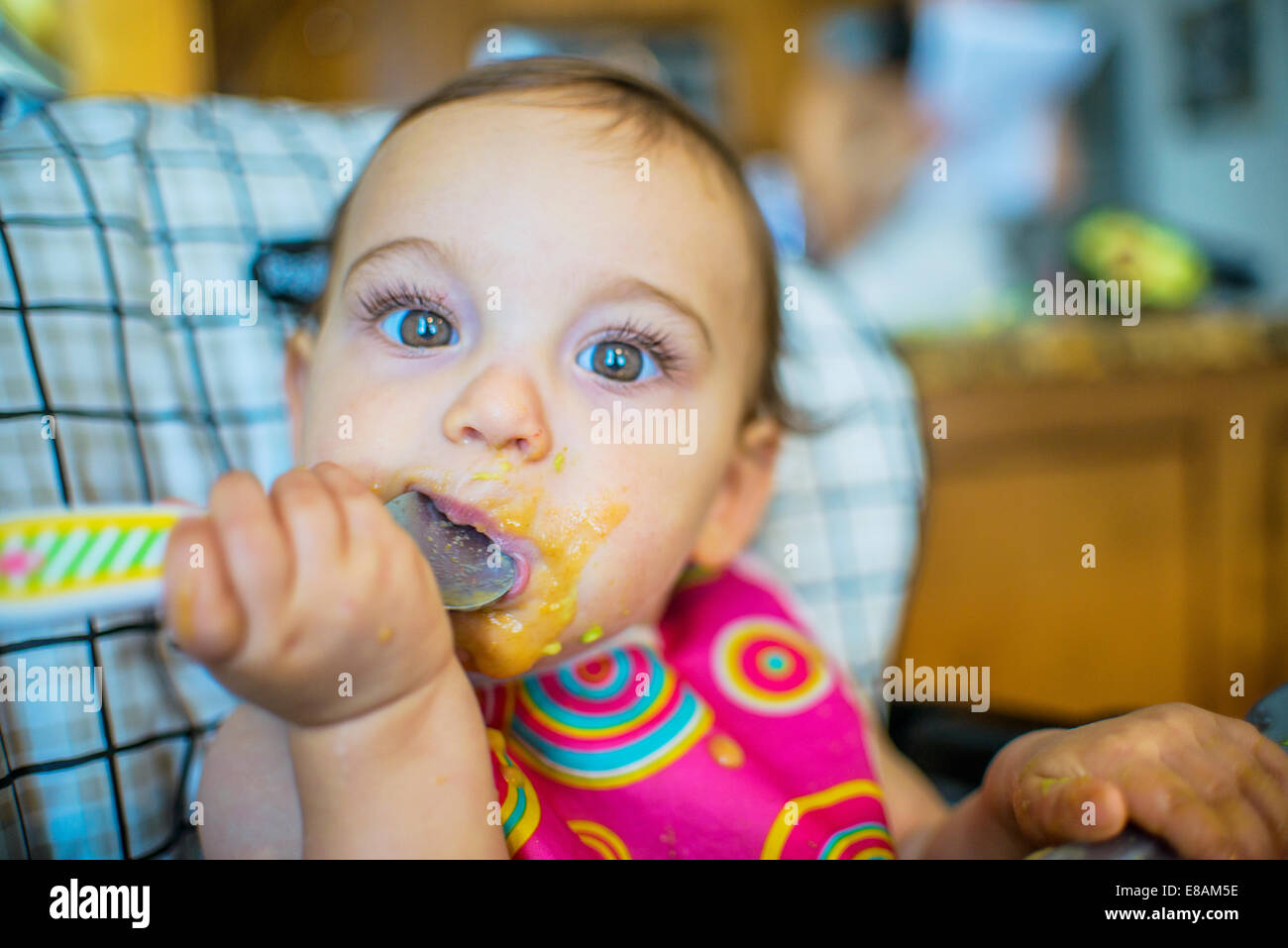 Portrait of baby girl eating from spoon Stock Photo