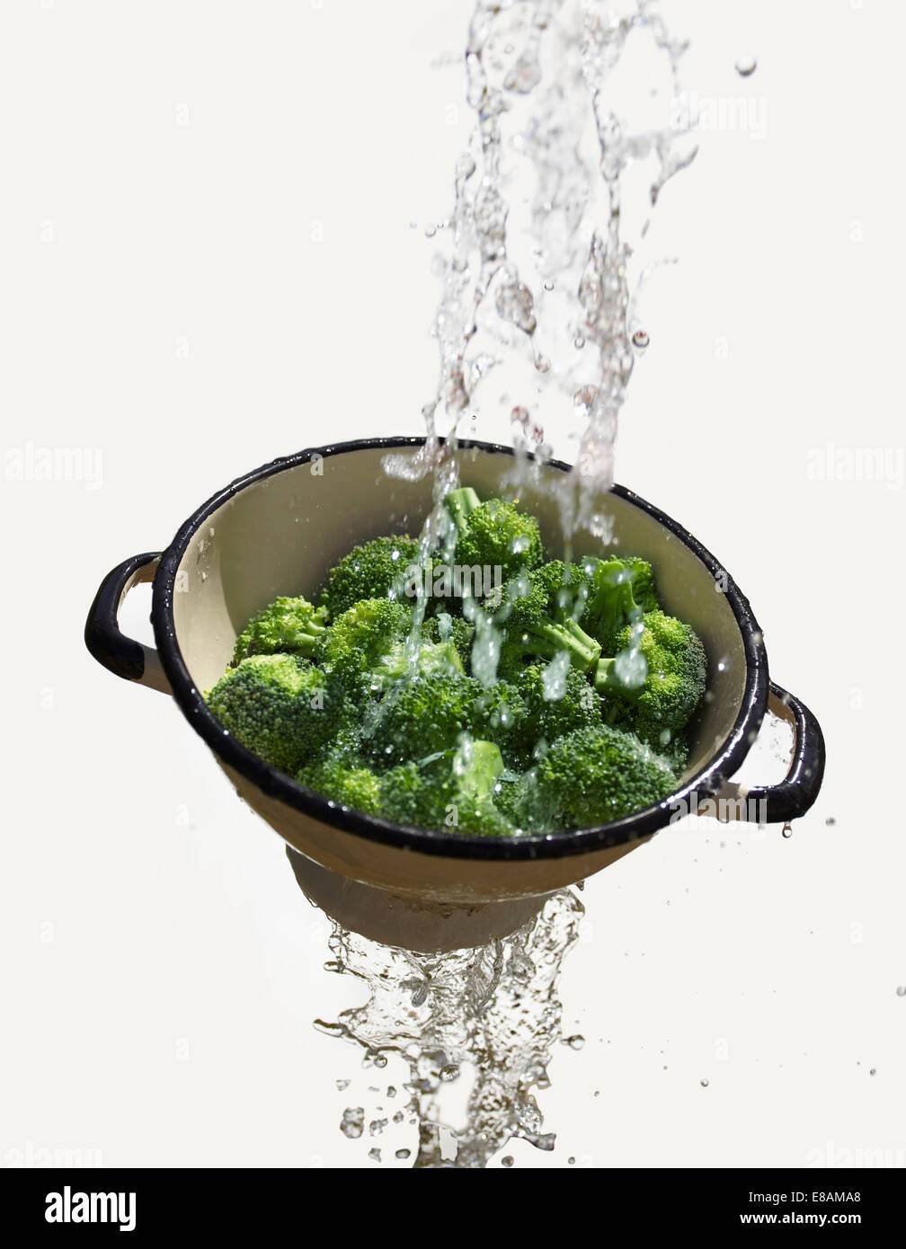 Water falling through colander with fresh broccoli Stock Photo