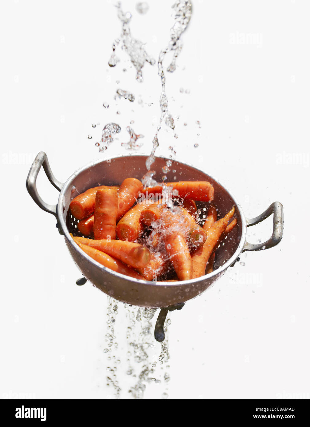 Water falling through colander with fresh carrots Stock Photo