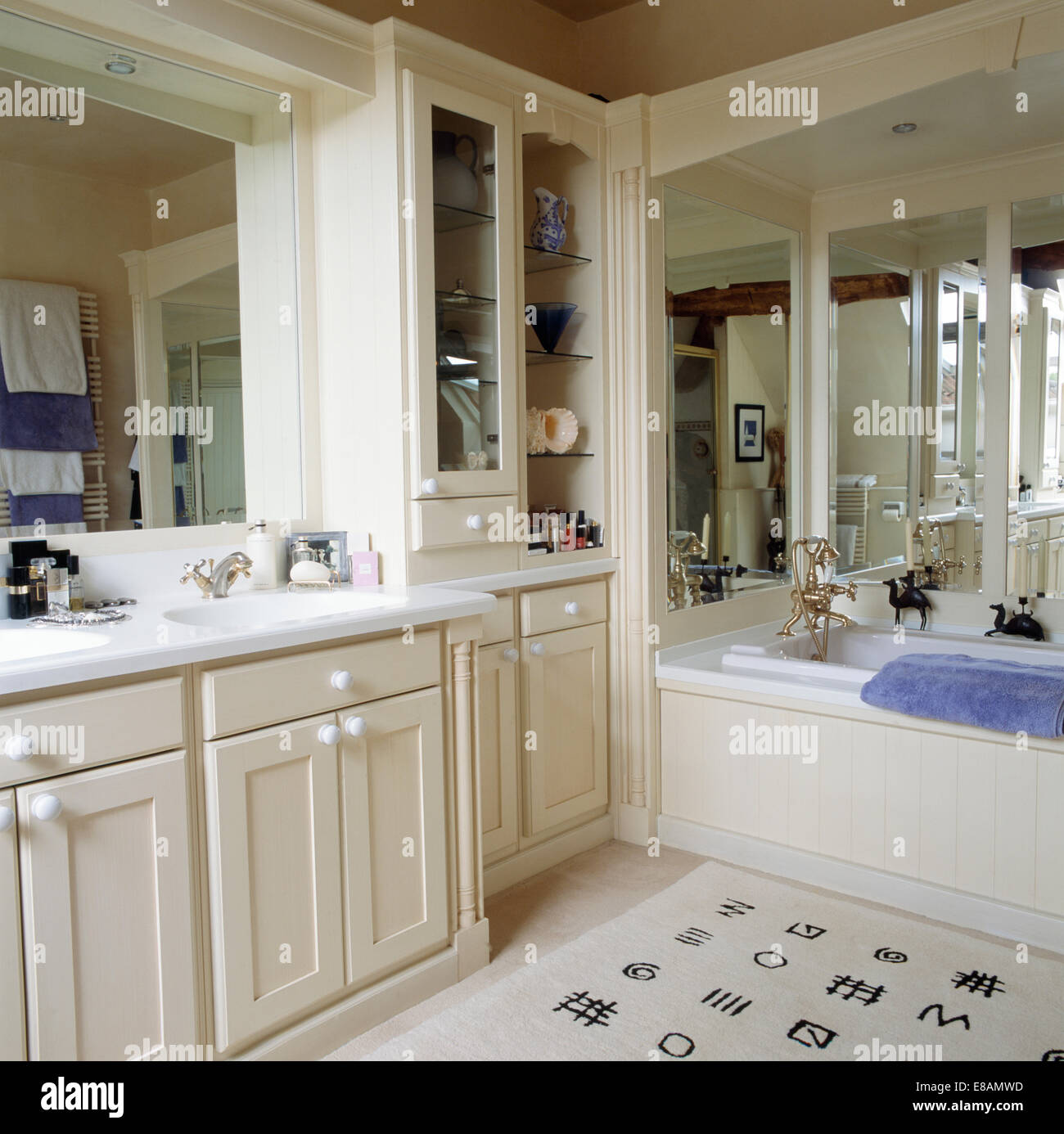 Mirrored wall above bath in white bathroom with fitteed and