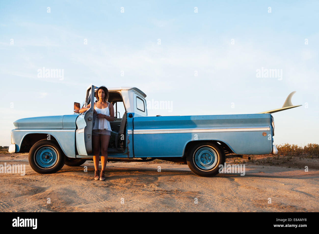 Portrait of young female surfer leaning on pick up truck door, Leucadia, California, USA Stock Photo