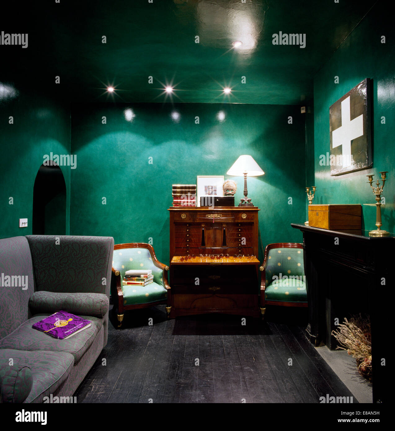 Grey sofa and antique in green living room with lacquered walls