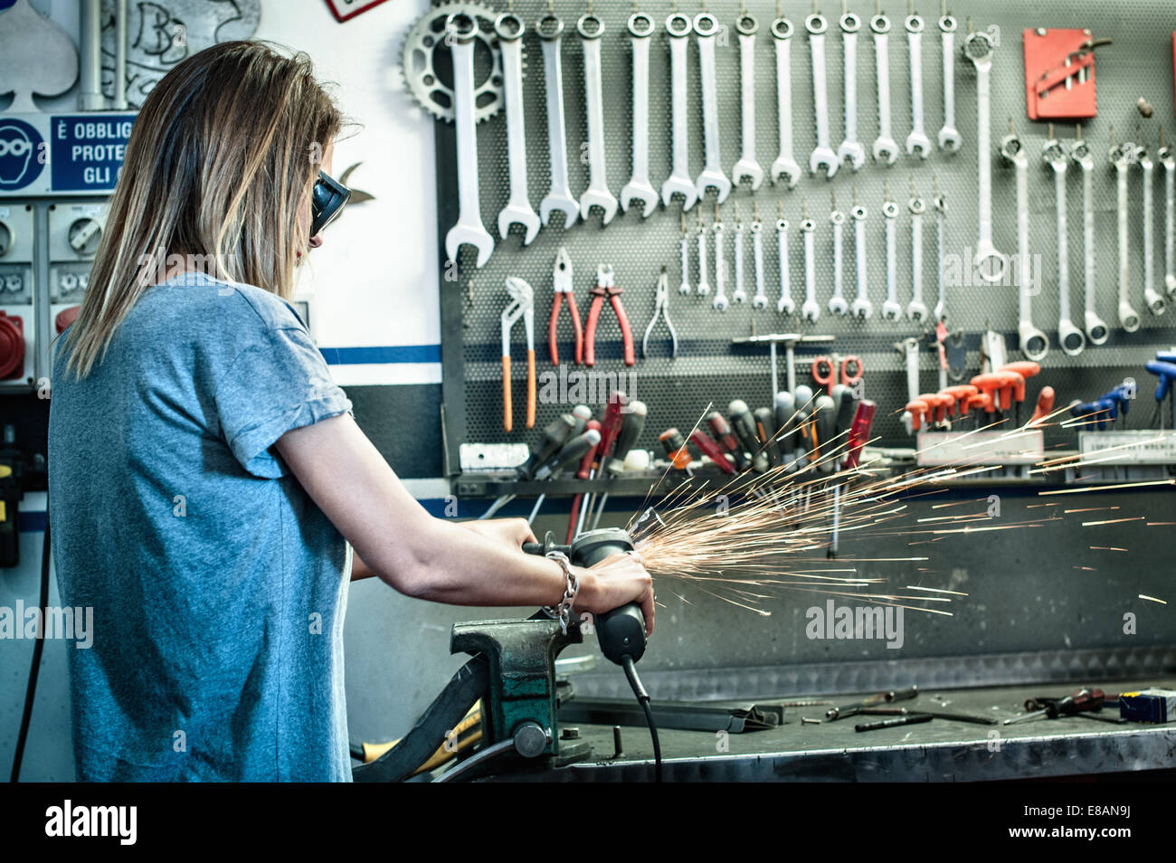 Female mechanic grinding metal in workshop Stock Photo
