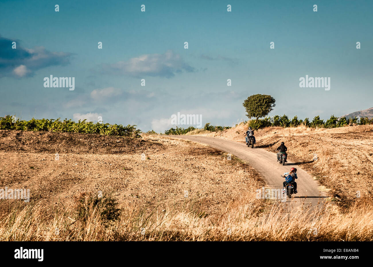 Rear view of four friends riding motorcycles on rural road, Cagliari, Sardinia, Italy Stock Photo