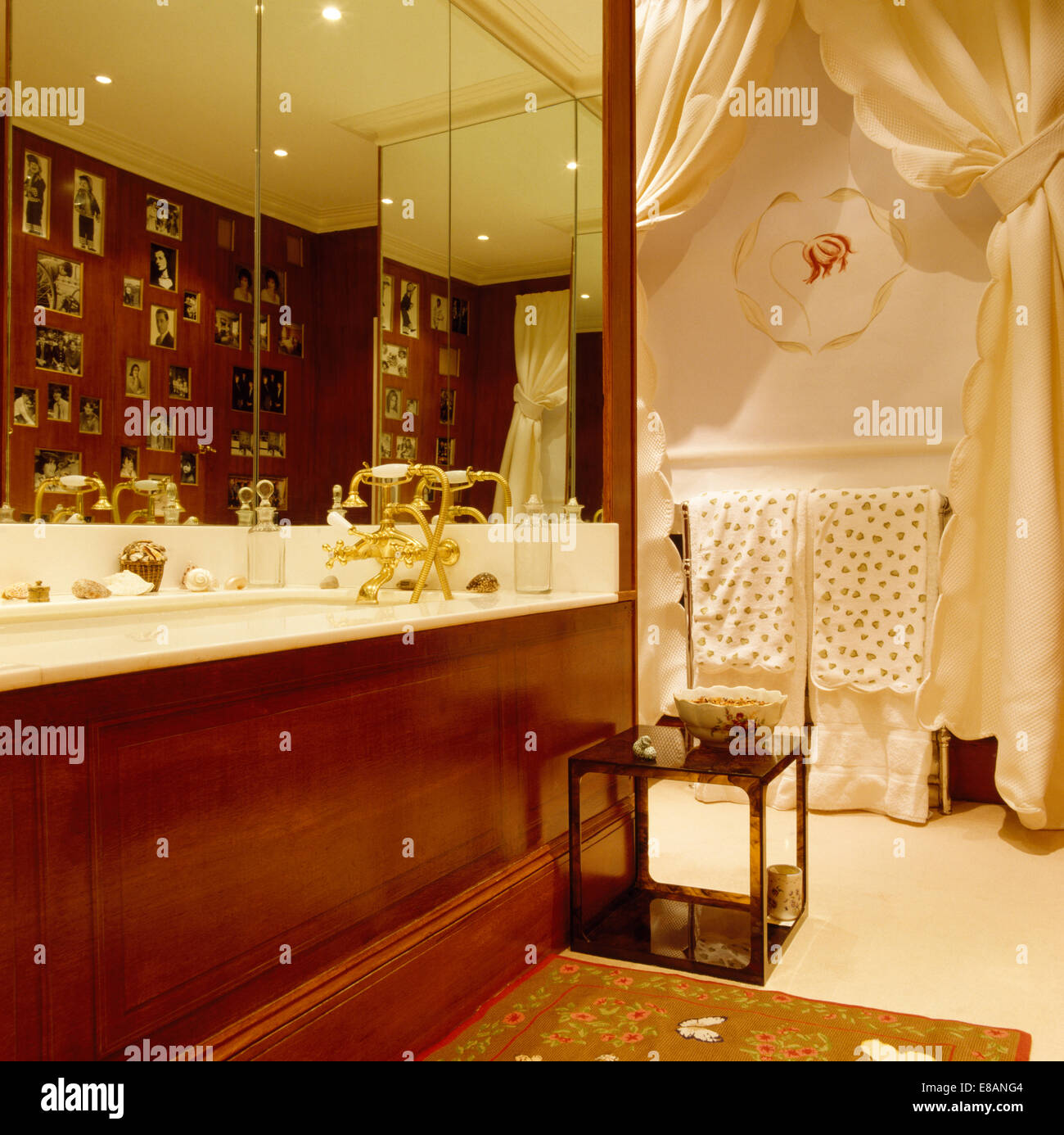 Mirrored wall above bath with polished wood panel in bathroom with