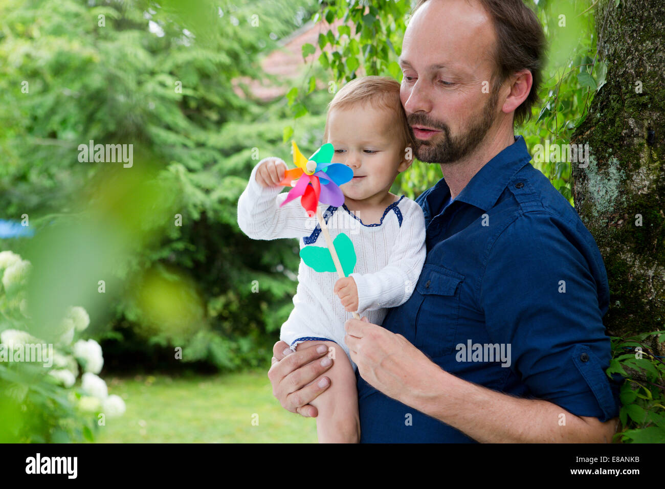 Father and baby daughter playing with pinwheel in garden Stock Photo