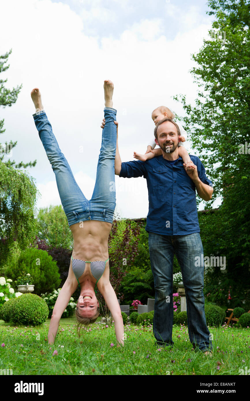 Mother doing handstand in garden next to family Stock Photo