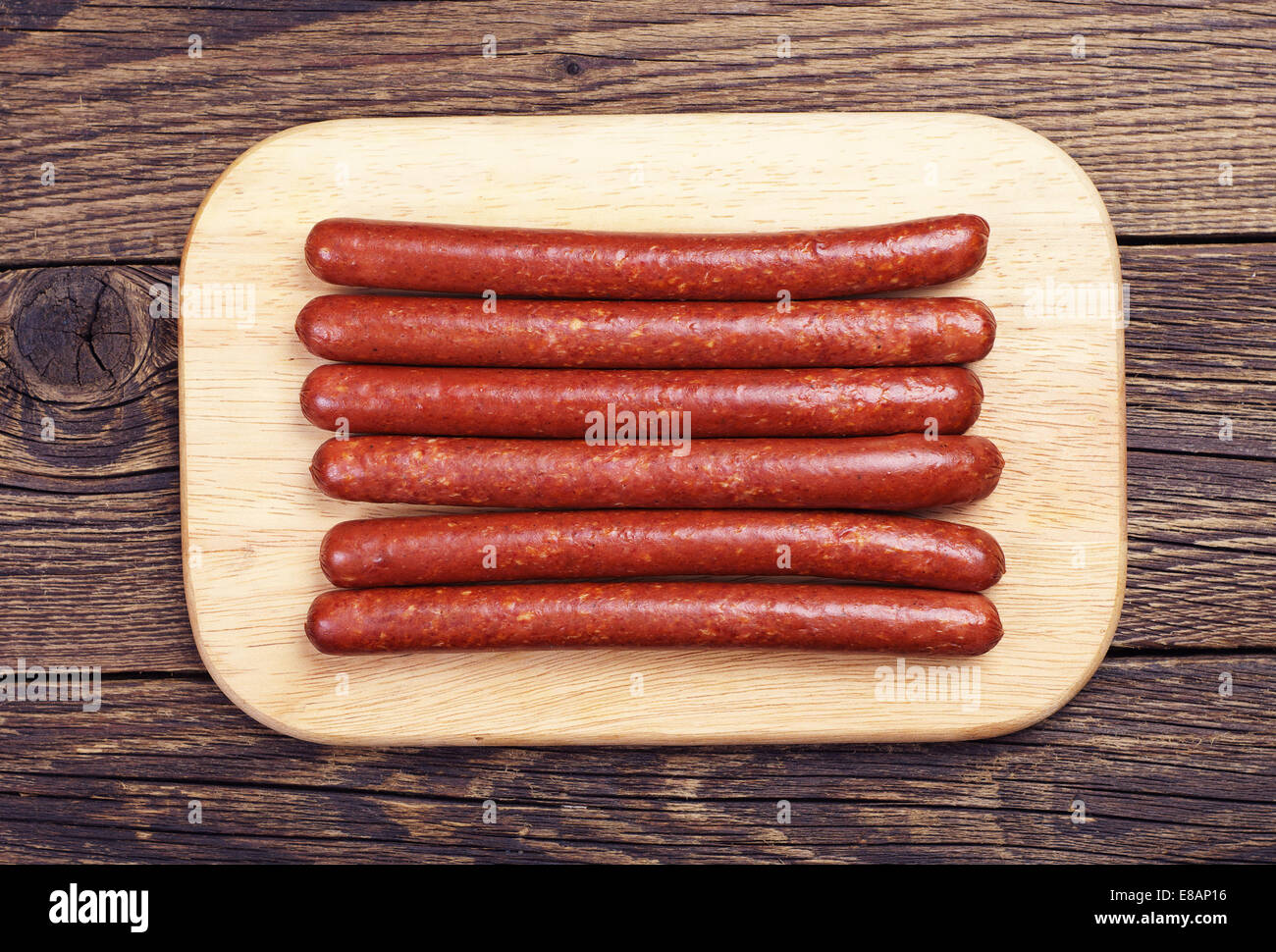 Thin smoked sausage on a cutting board. Top view Stock Photo
