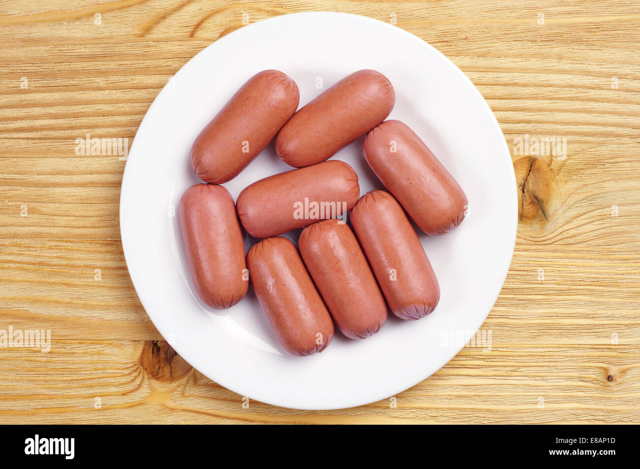 Small sausages in a plate on a wooden background, Top view Stock Photo