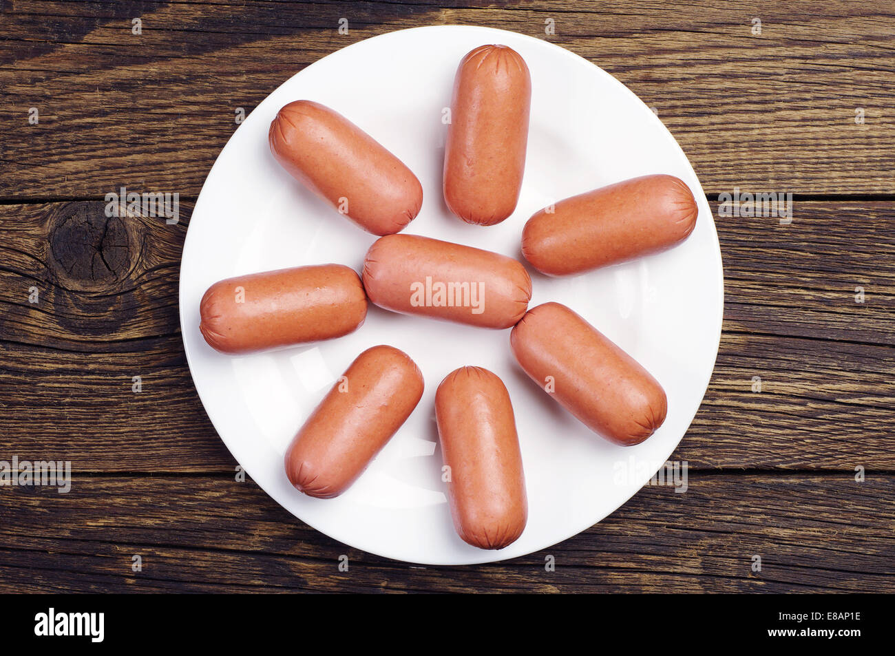 Top view on sausages in a plate on a wooden table Stock Photo