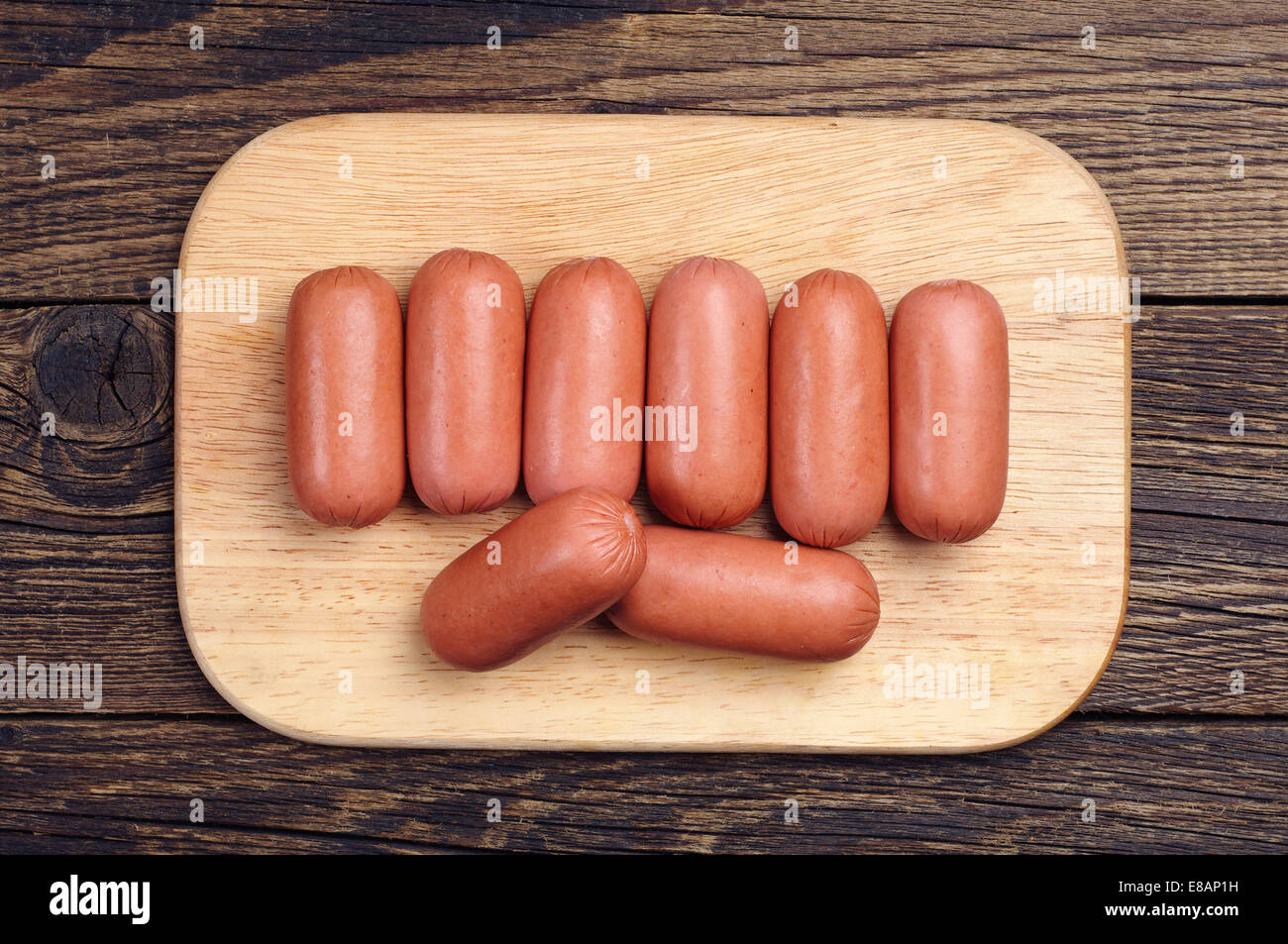 Small sausages on a cutting board on wooden table Stock Photo
