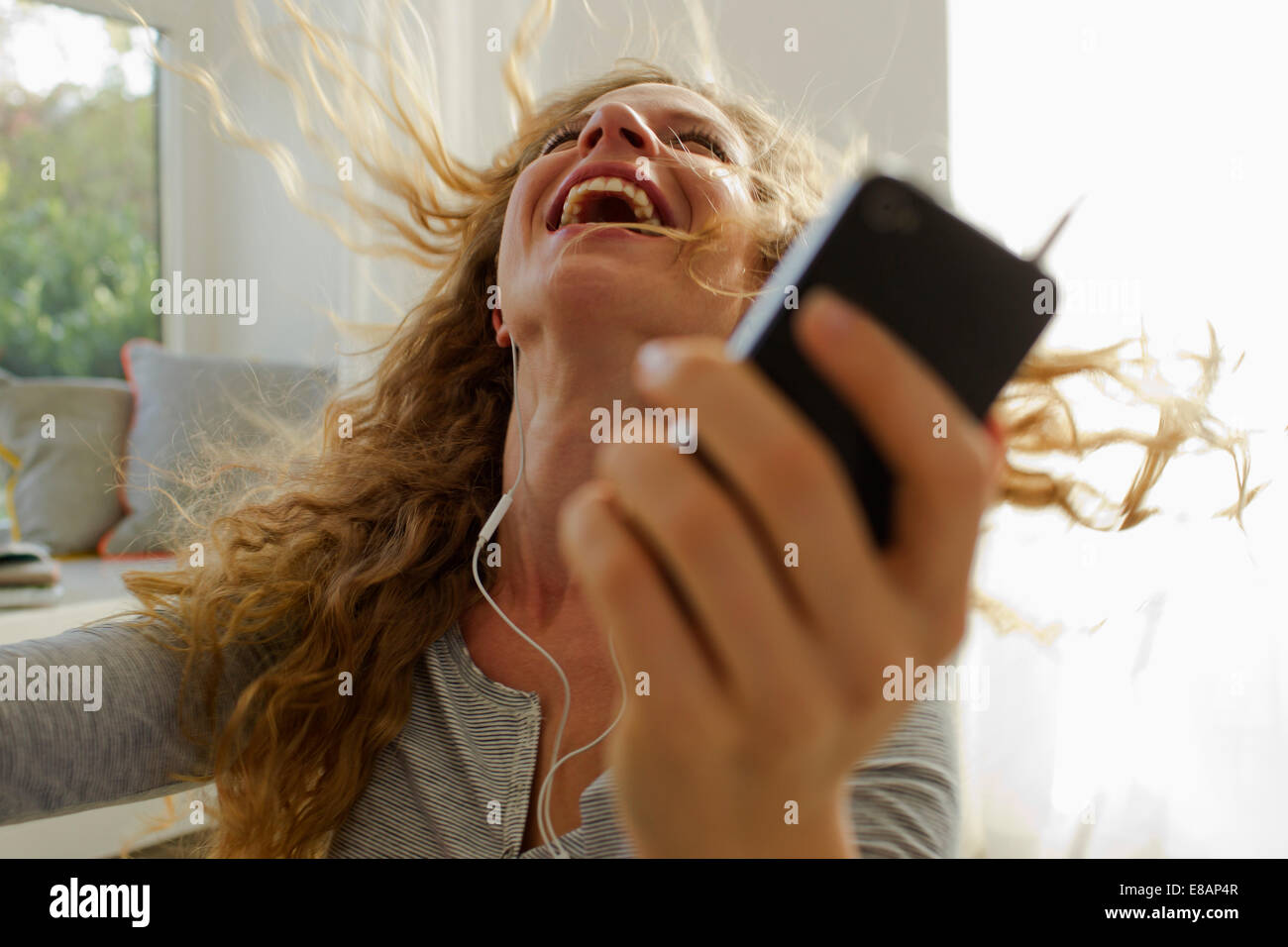 Woman dancing to music on smartphone Stock Photo