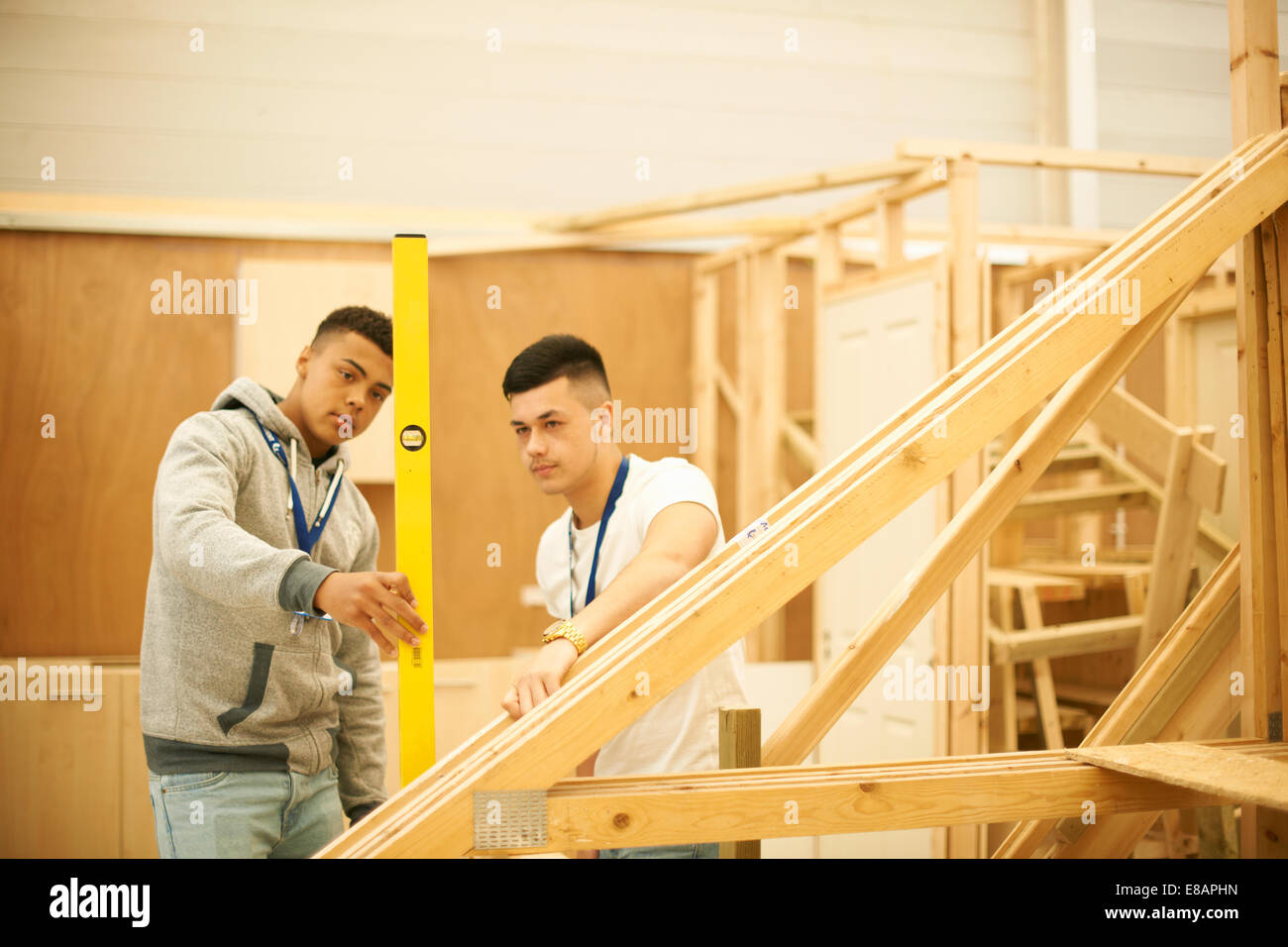 Two male college students using spirit level in woodworking workshop Stock Photo