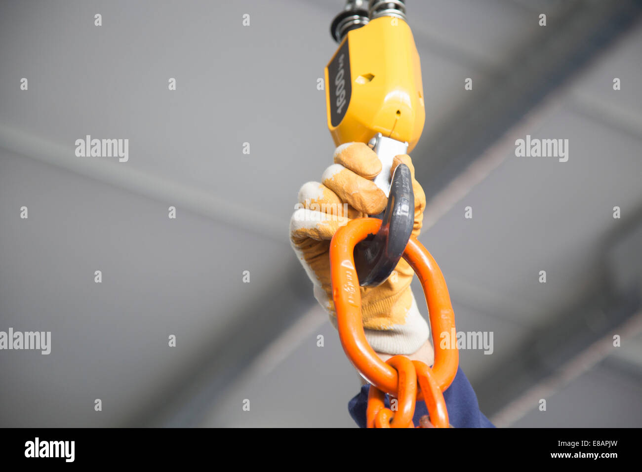 Worker adjusting chain hoist in industrial plant Stock Photo