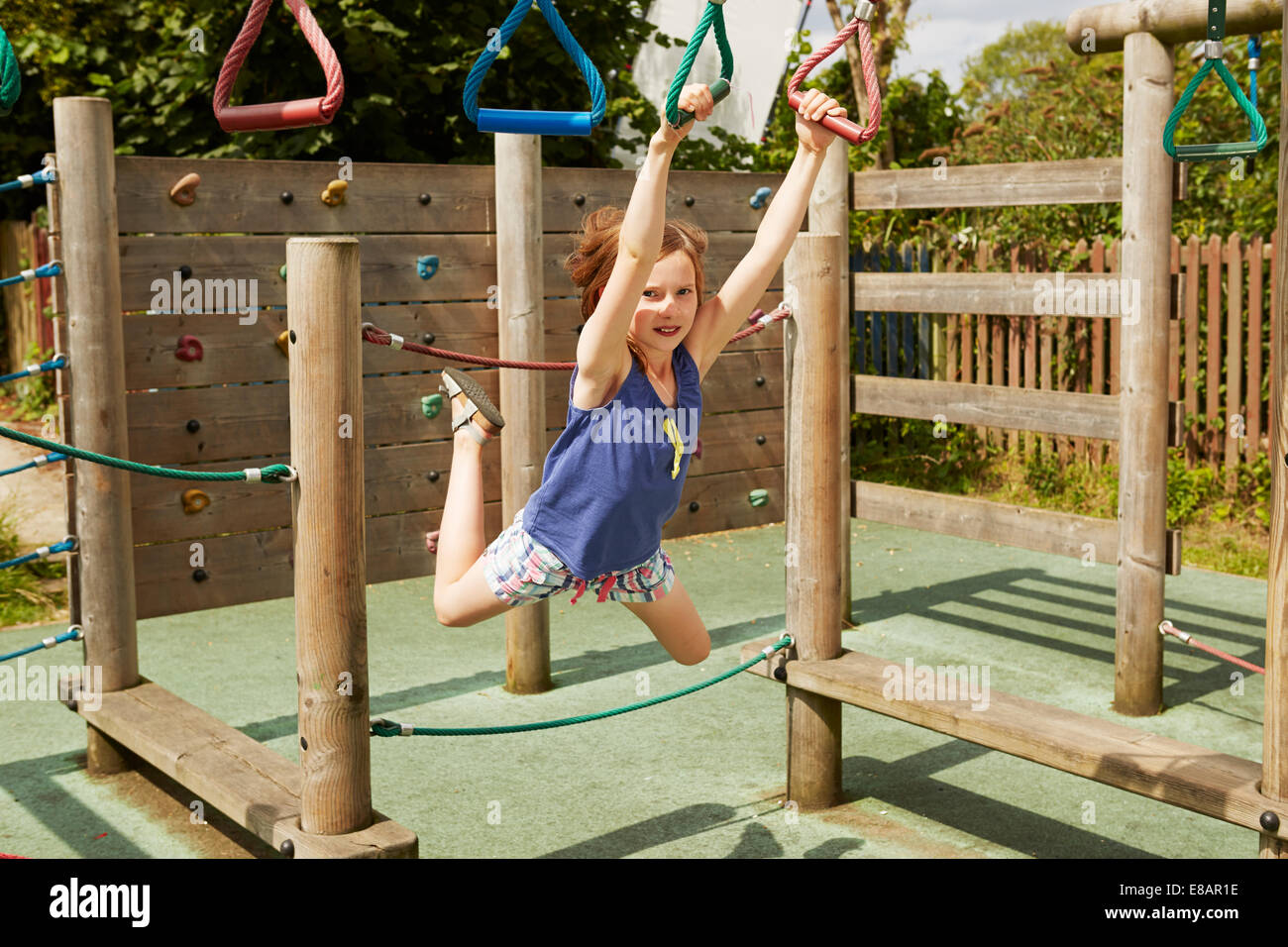 Girl energetically playing on swings in playground Stock Photo