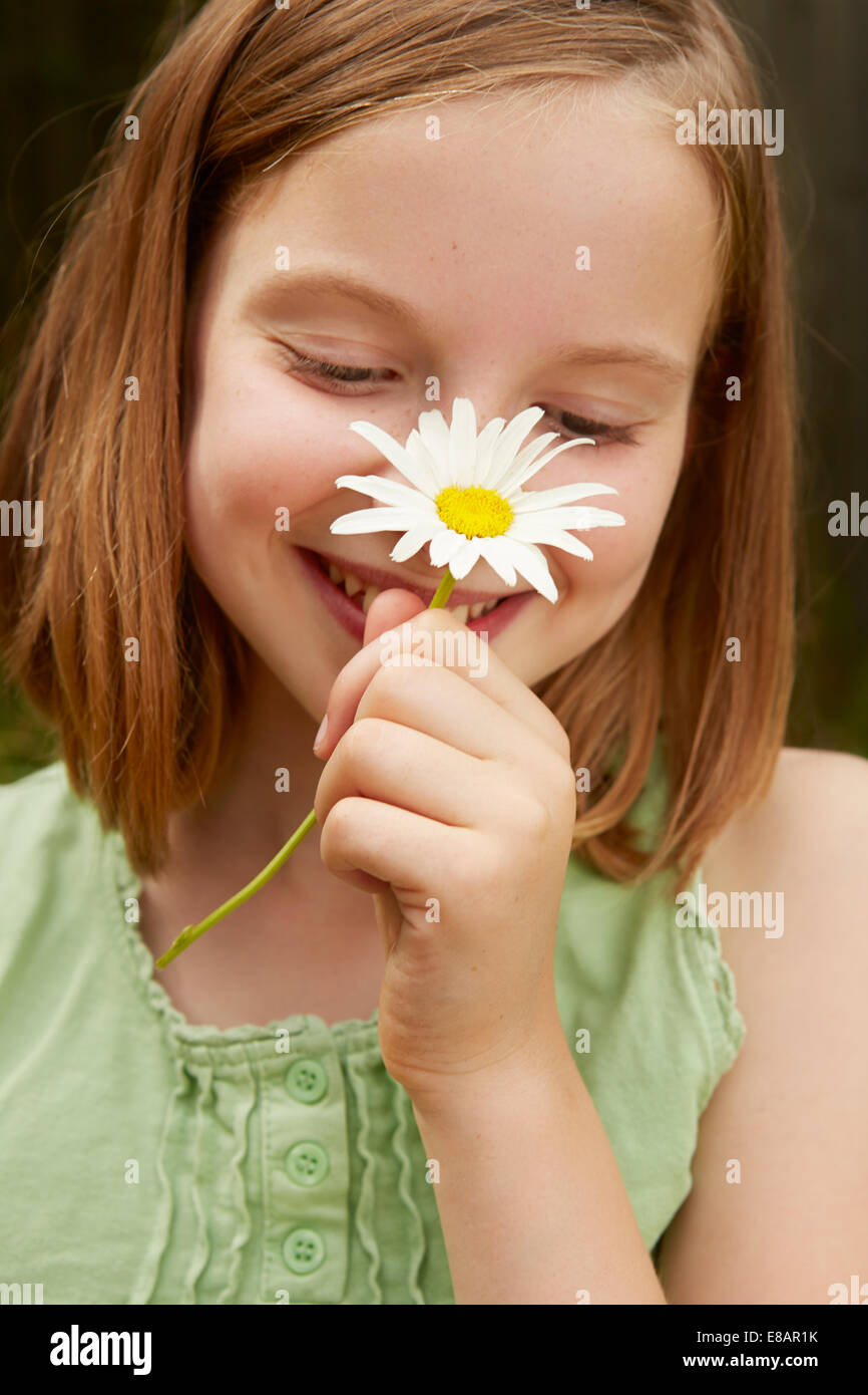Portrait of girl in garden holding up daisy Stock Photo