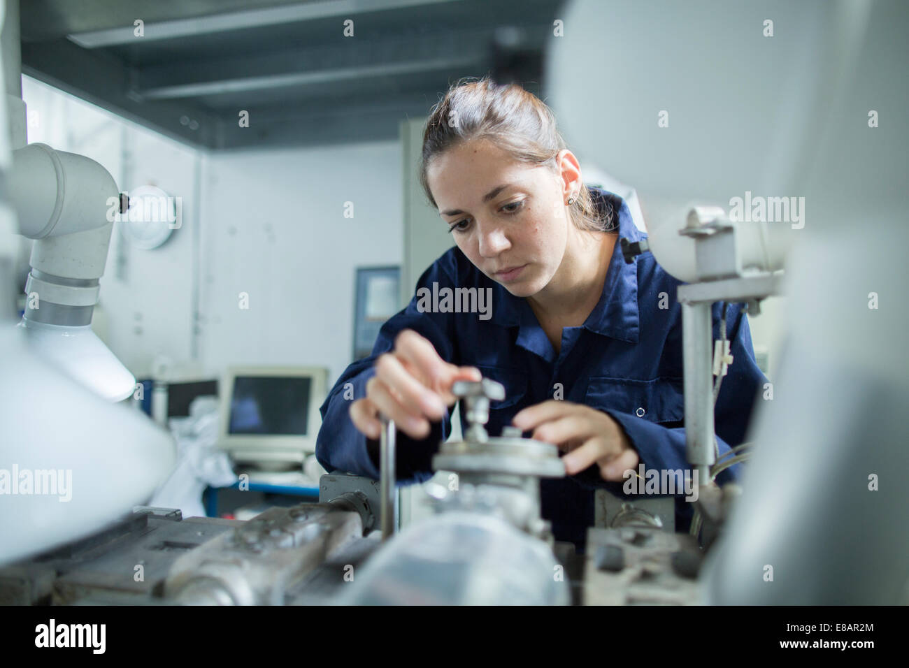 Female engineer turning valves on factory industrial piping Stock Photo