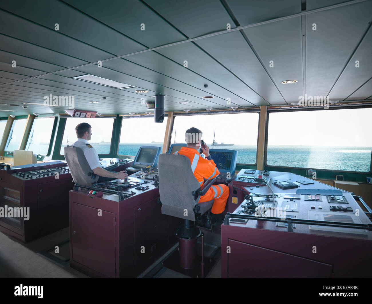 Captain and worker on bridge steering ship at sea Stock Photo