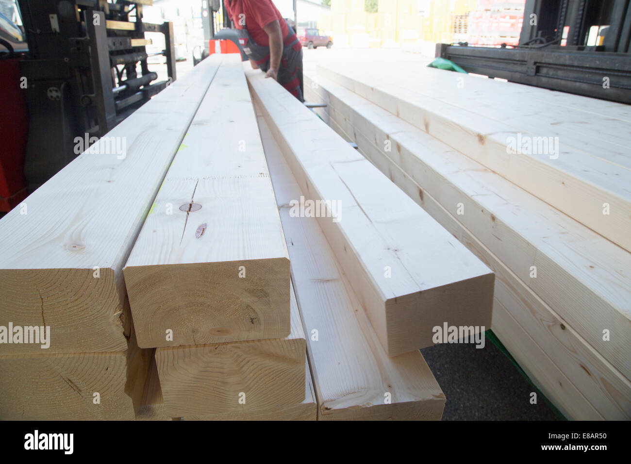 Male warehouse worker stacking wooden planks for hardware store Stock Photo