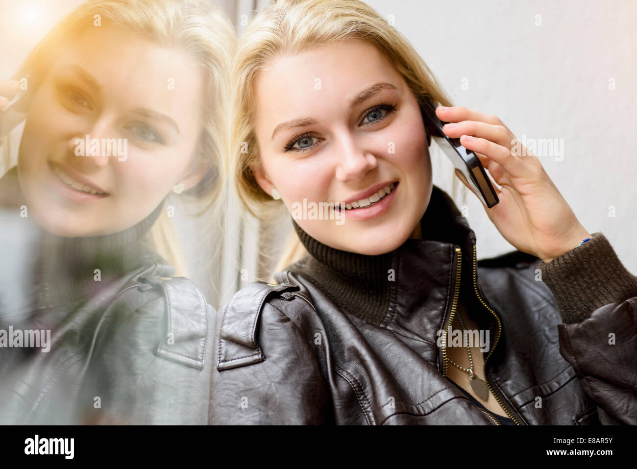 Portrait of young woman chatting on smartphone by window Stock Photo