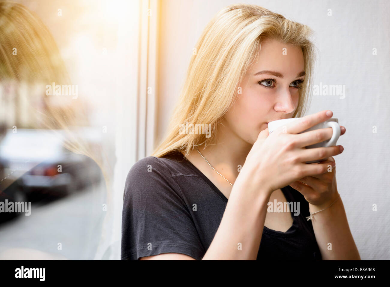 Young woman drinking coffee in window seat Stock Photo
