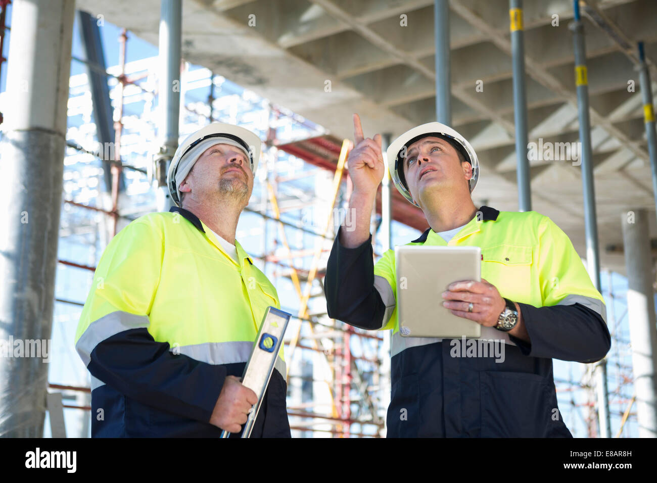Site manager and builder looking up on construction site Stock Photo