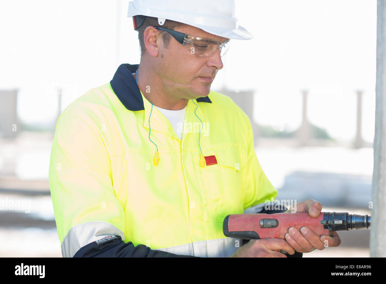 Builder using electric drill on construction site Stock Photo