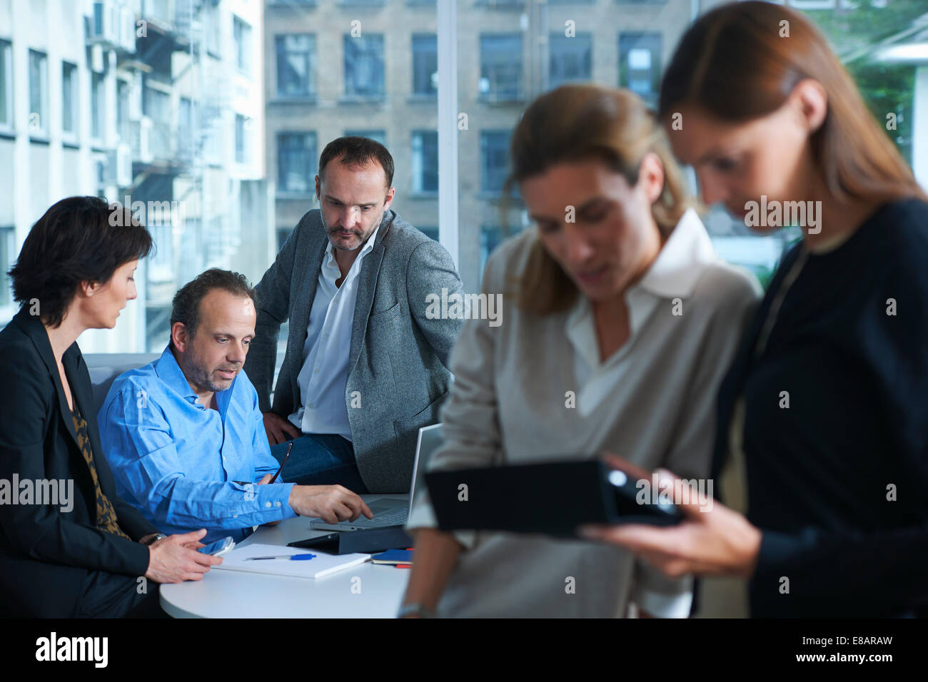 Five businesswomen and men working in busy office Stock Photo