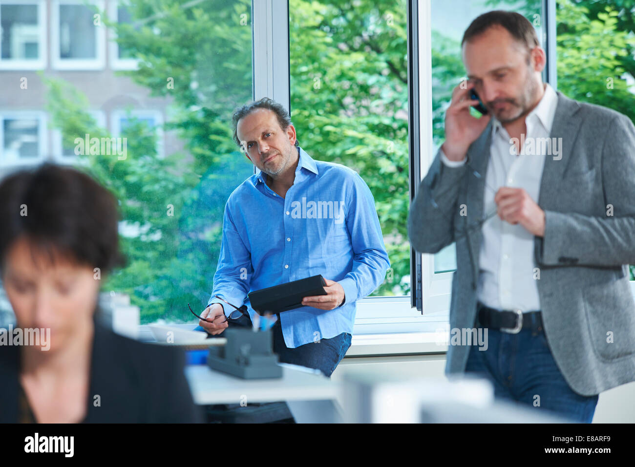 Three business colleagues working in busy office Stock Photo
