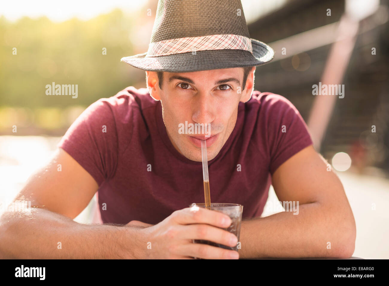 Young man wearing hat drinking through straw Stock Photo