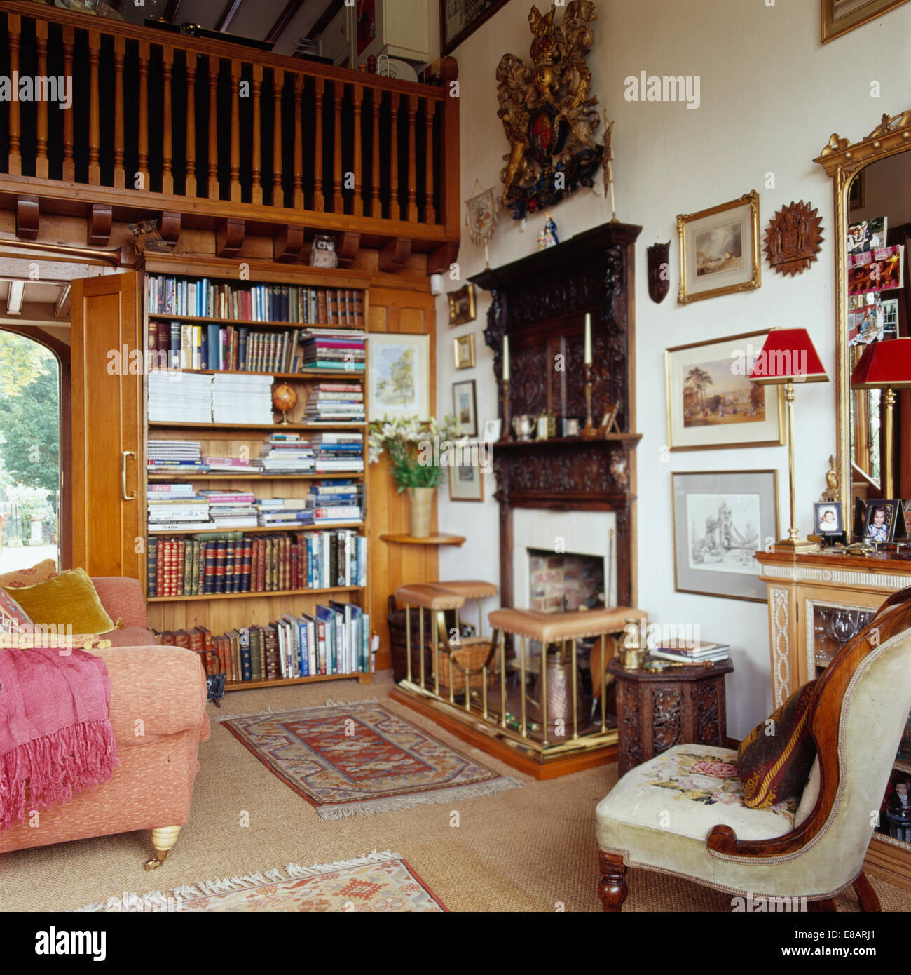 Traditional country study living room with mezzanine and fitted bookshelves close to fireplace with club fender Stock Photo