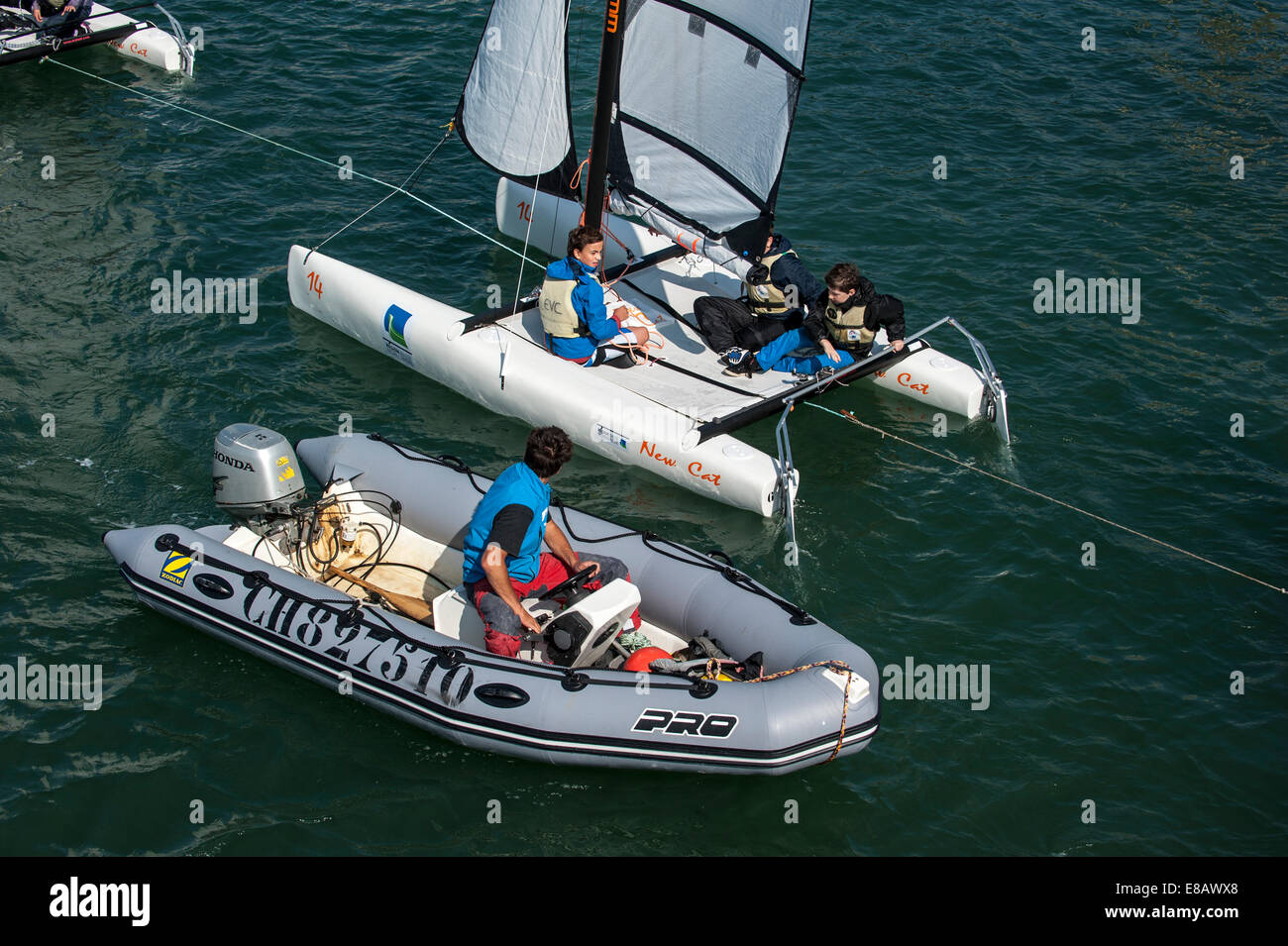 Teacher in inflatable boat teaching school children on catamaran how to