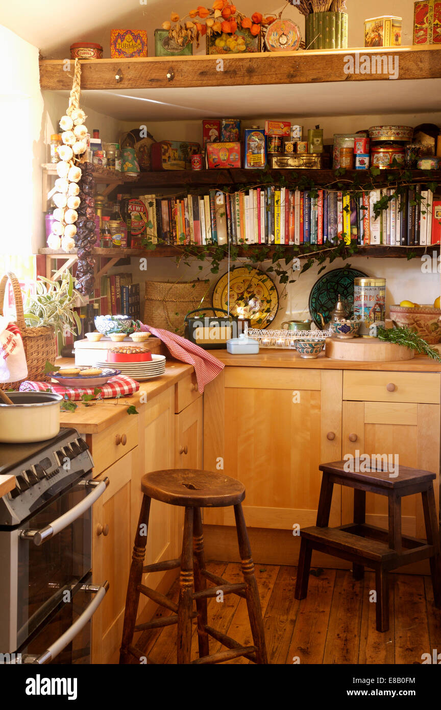 Old wooden stools in country kitchen with pine units and cookery books