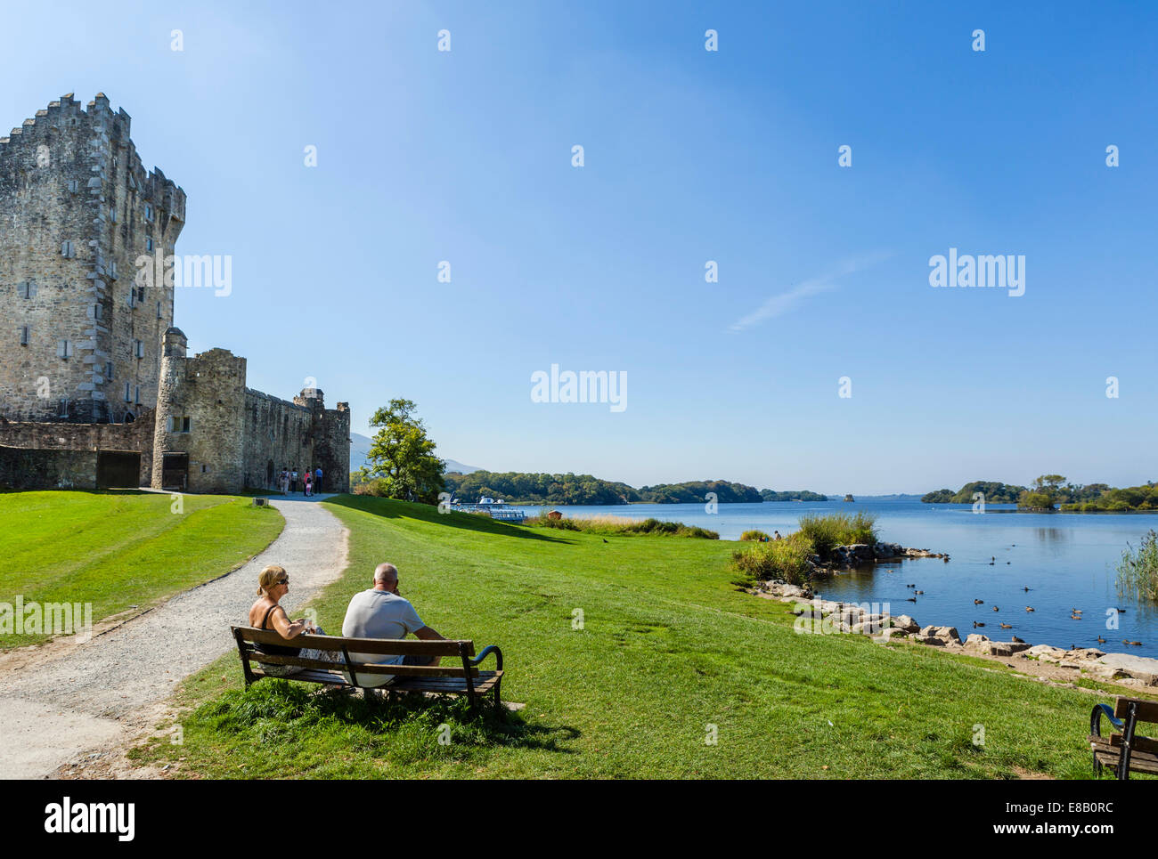 Couple on bench in front of Ross Castle on shores of Lough Lean, Killarney National Park, County Kerry, Republic of Ireland Stock Photo