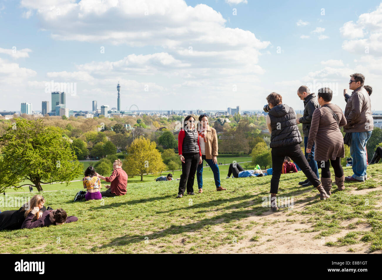 Person photographing friends on Primrose Hill with the London skyline in the distance, England, UK Stock Photo