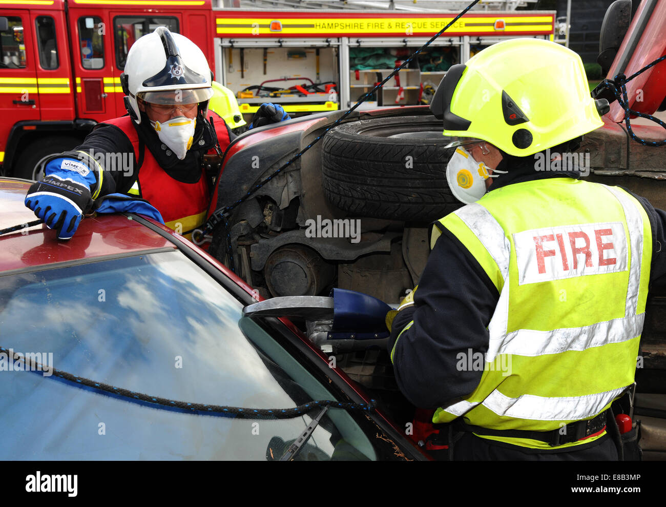 Fire service jaws of life cutting at a car crash Fire service officers cut a collision victim free from a car Stock Photo