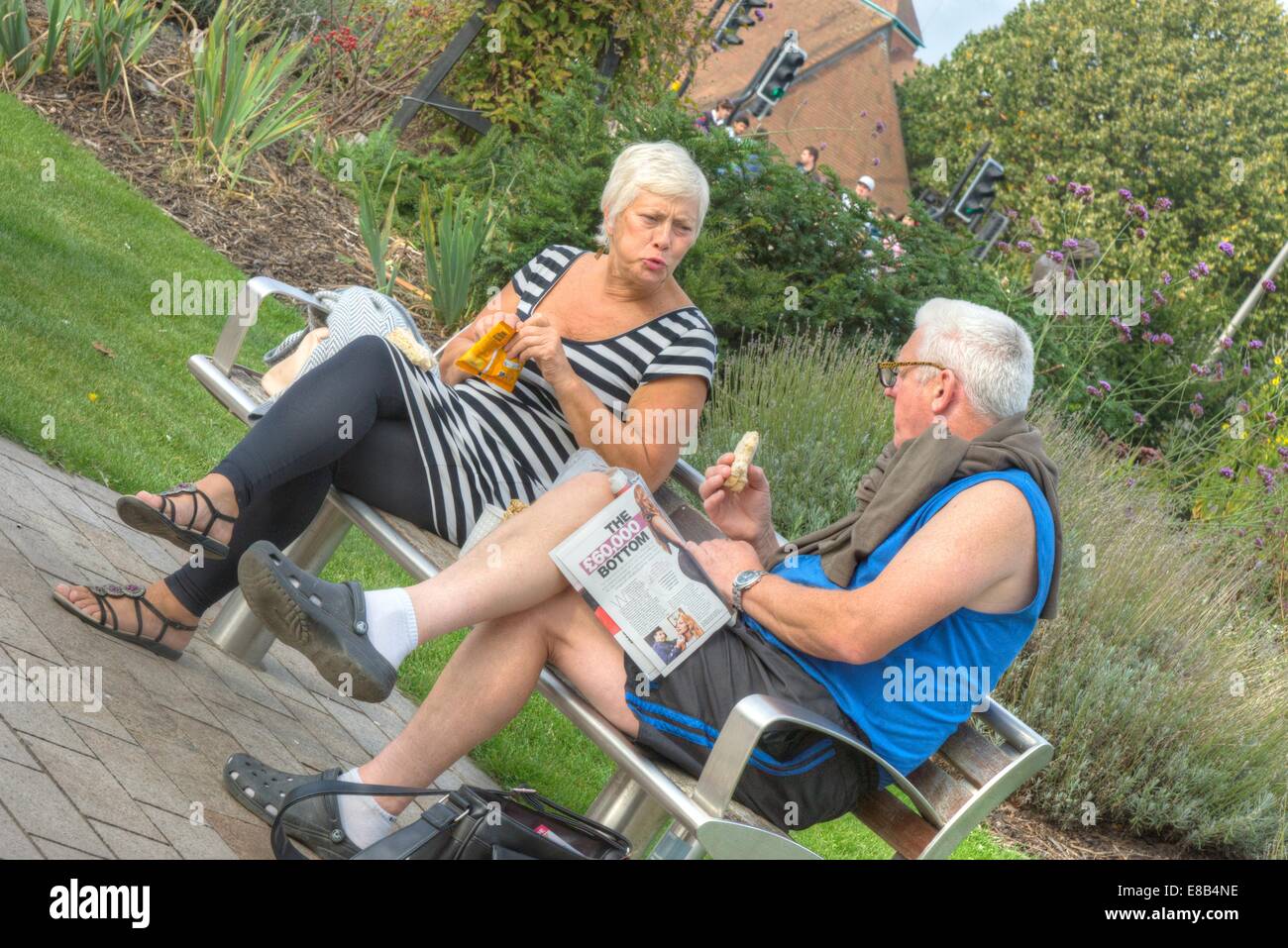 two people on park bench eating Stock Photo