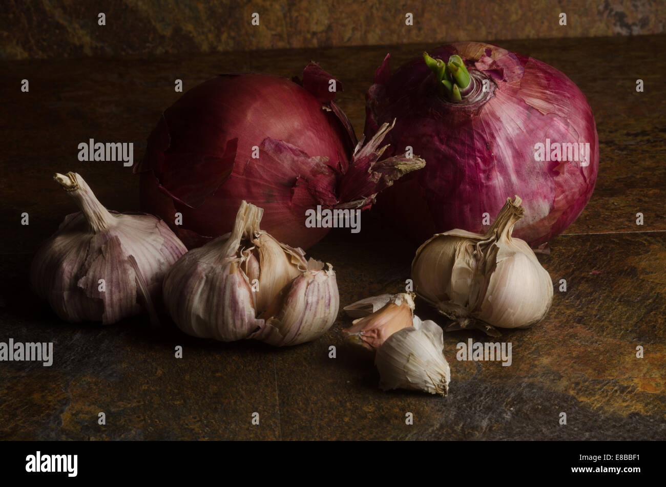 detail of red onions and garlic over a stone textured table. still life Stock Photo