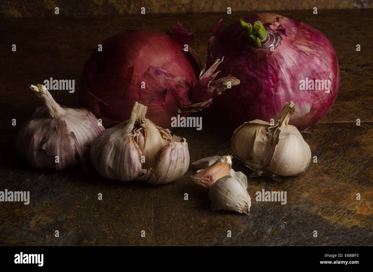 detail of red onions and garlic over a stone textured table. still life Stock Photo